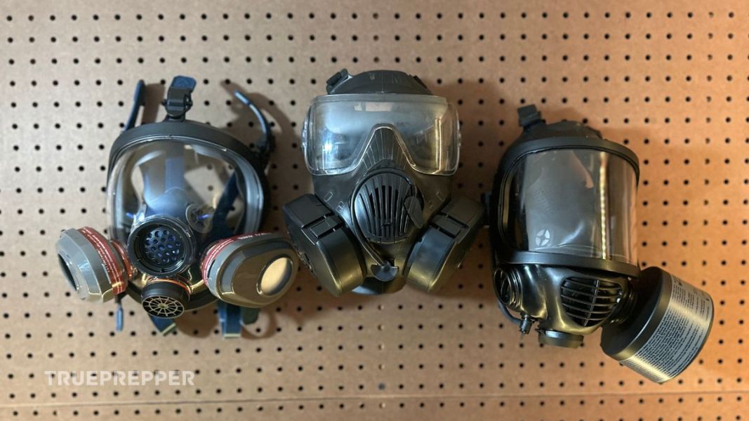 Parcil Safety, Avon M50, and Mira CM-6M Gas Masks hanging on brown pegboard.